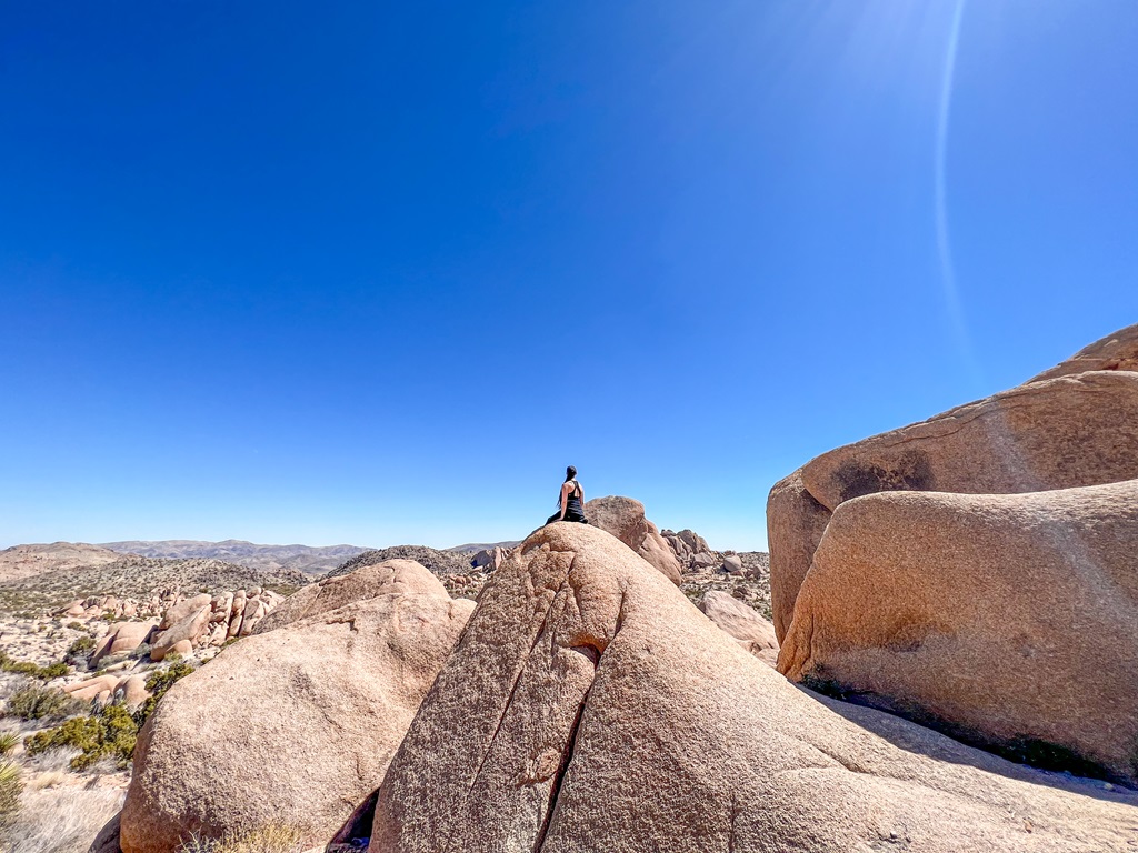 Woman sitting on a big boulder along the Split Rock Trail in Joshua Tree National Park.