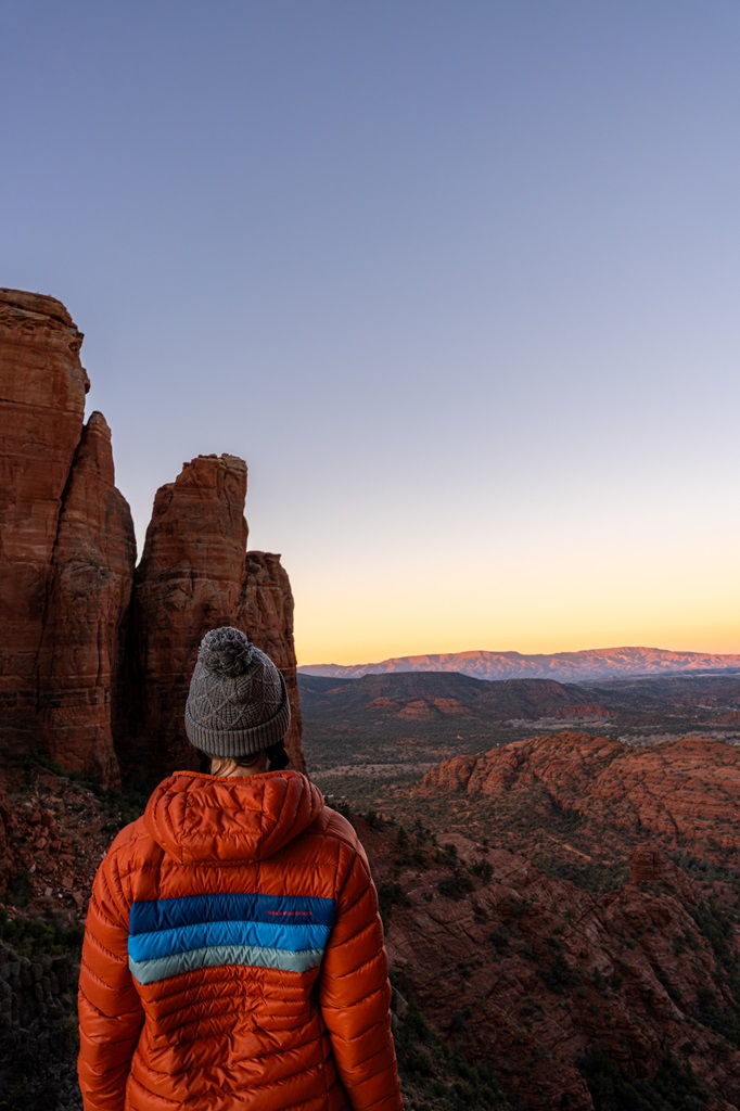 Woman standing at Cathedral Rock watching the sunrise in Sedona.