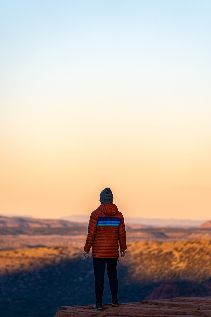 Woman standing on a rocky outcrop at Cathedral Rock during sunrise in Sedona.