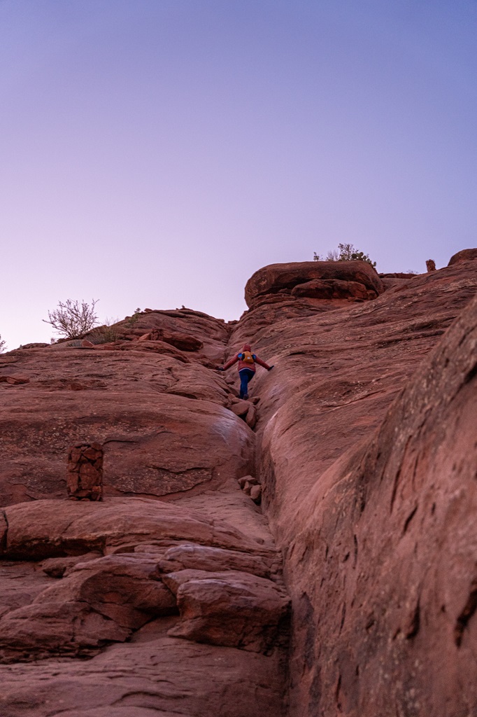 Woman rock scrambling along the Cathedral Rock Trail in Sedona.