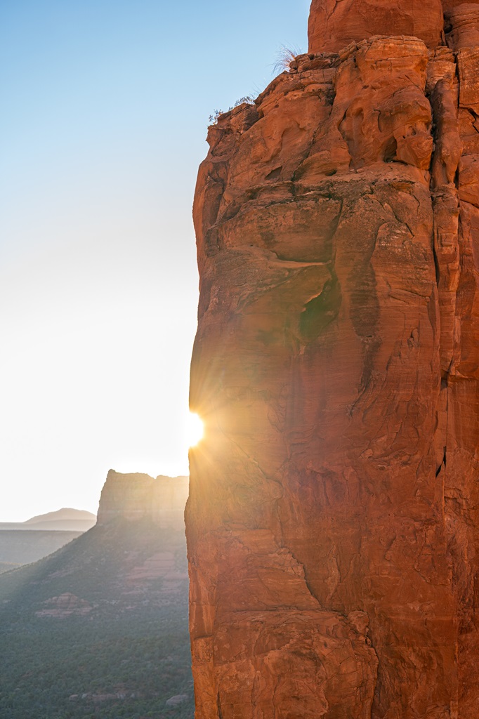 Sun peaking behind Cathedral Rock in Sedona during sunrise.