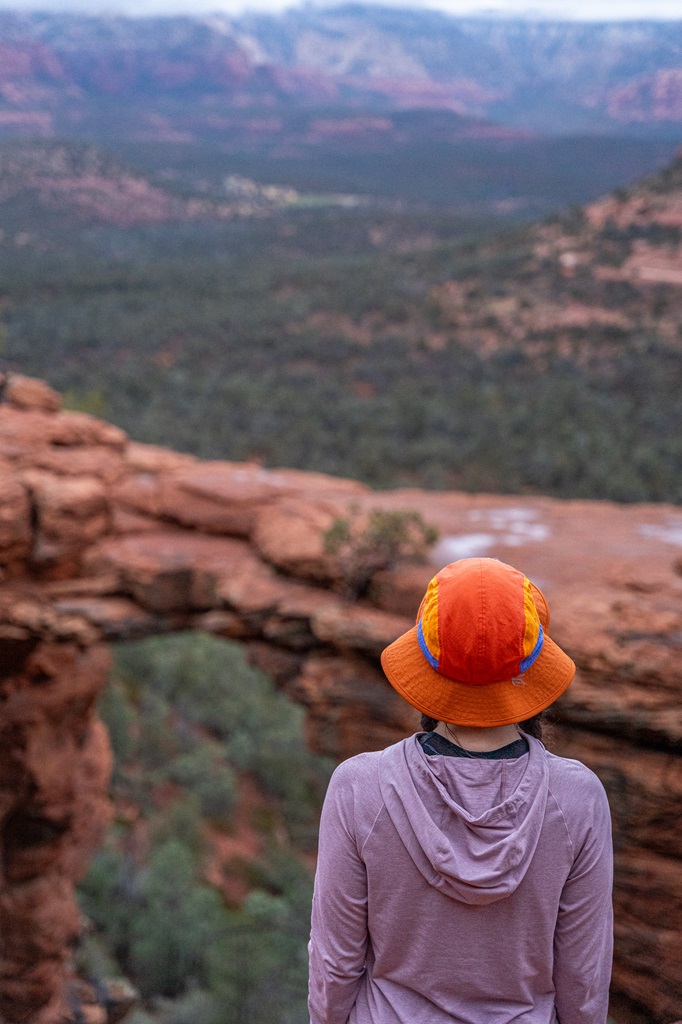 Woman standing on a rocky outcrop in front of Devil's Bridge in Sedona.