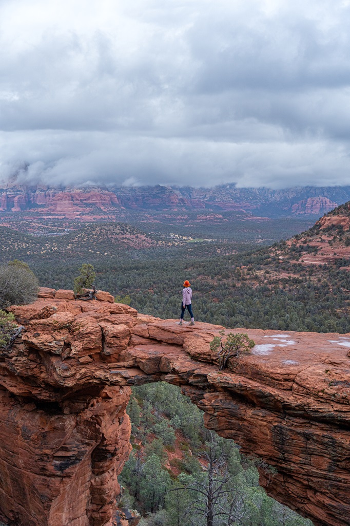 Woman walking across Devil's Bridge in Sedona on a cloudy, rainy day.