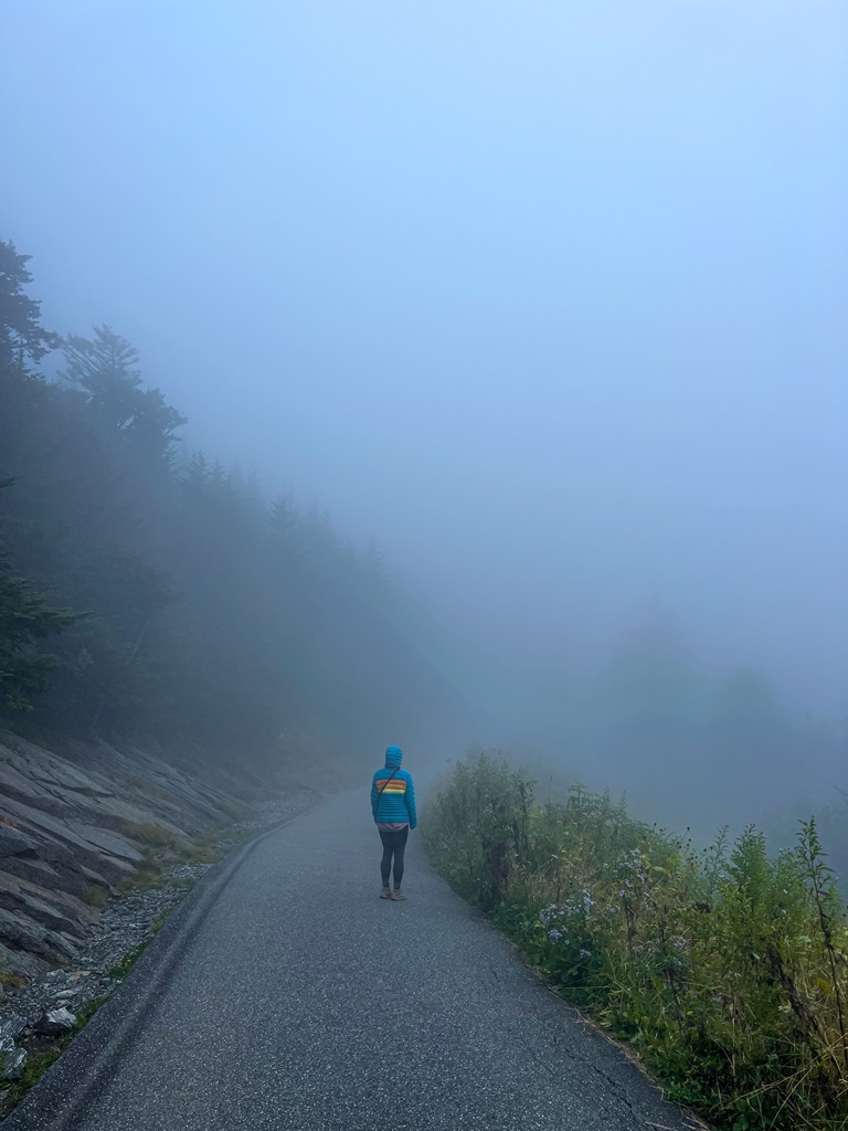 Woman standing on the Kuwohi observation tower trail during a foggy morning.