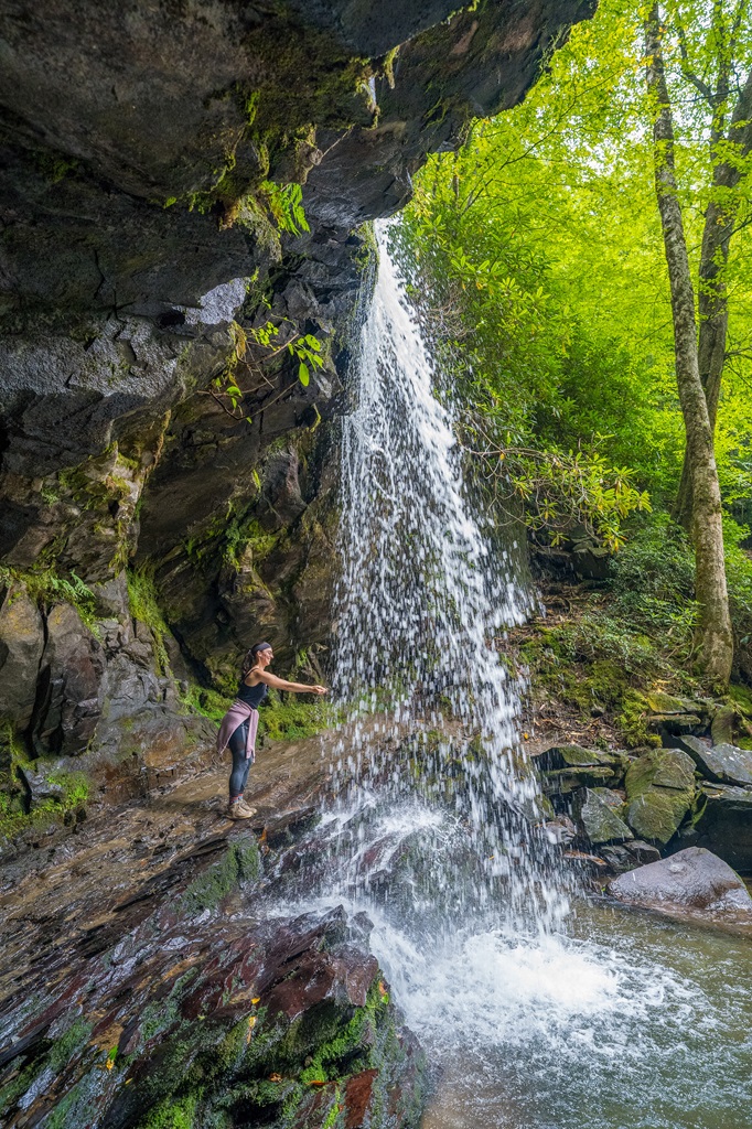 Woman standing behind Grotto Falls in Great Smoky Mountains National Park.