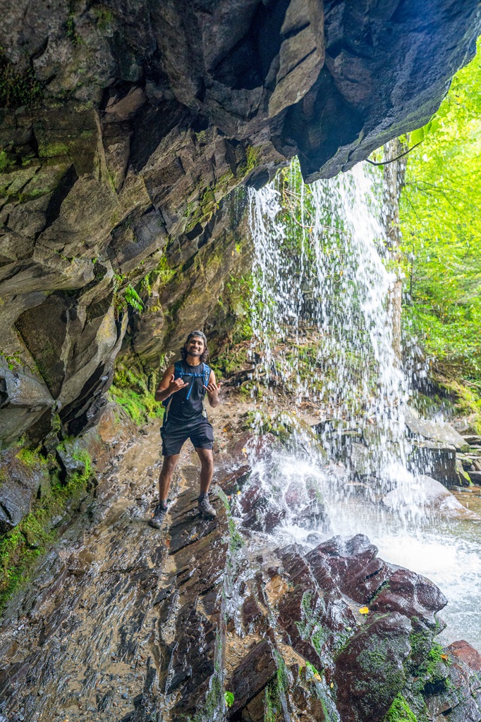 Man standing behind Grotto Falls located in the Great Smoky Mountains.