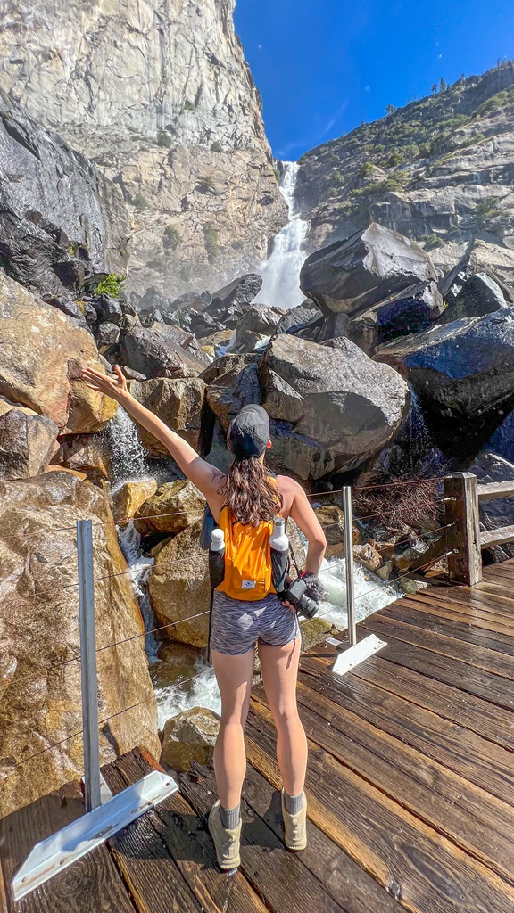 Woman standing on a footbridge in front of Wapama Falls.