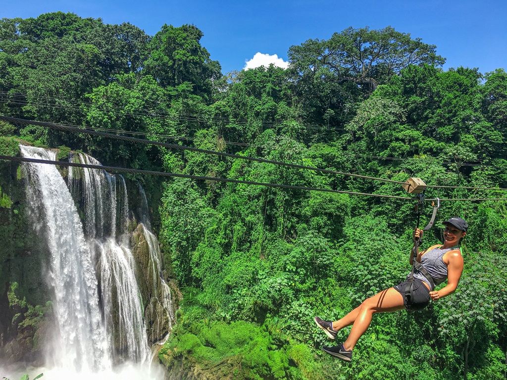 Woman ziplining past a waterfall in Honduras.