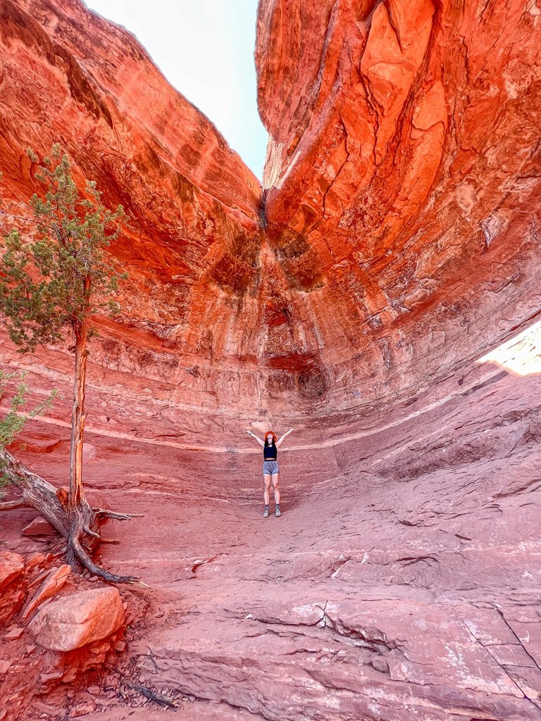 Woman standing in the Birthing Cave with hands in the air.