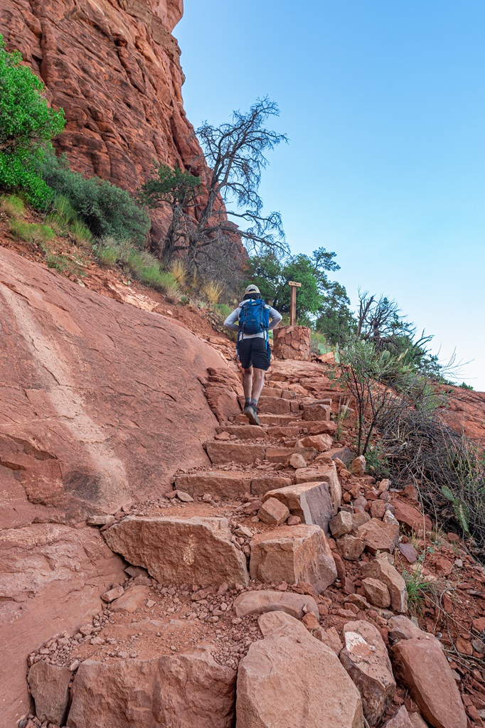 Man hiking up the last section of stairs before reaching the summit of Cathedral Rock.