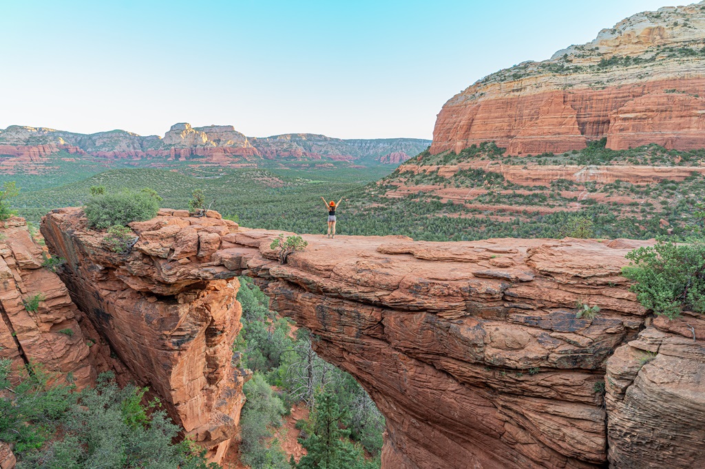 Woman standing on Devil's Bridge with hands in the air.