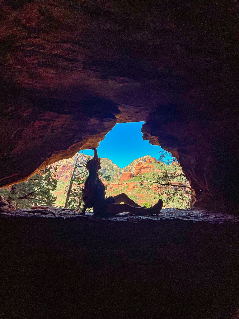 Woman posing on a small arch-window spot inside the Soldiers Pass Cave.