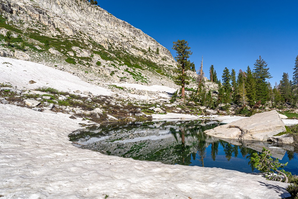 A small unnamed lake or pond along the Lakes Trail surrounded by snow.