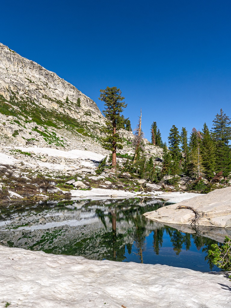 A small unnamed lake or pond along the Lakes Trail surrounded by snow.