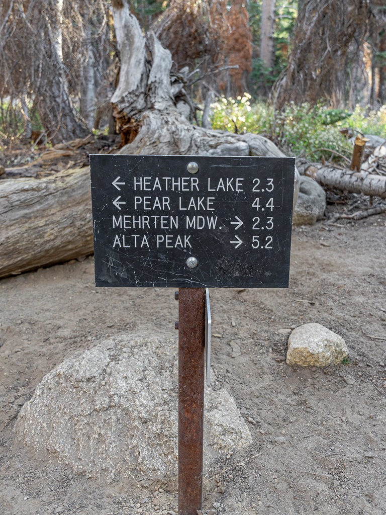 Trail sign with arrows pointing to the left towards Heather and Pear Lake and another arrow pointing to the right towards Alta Peak.