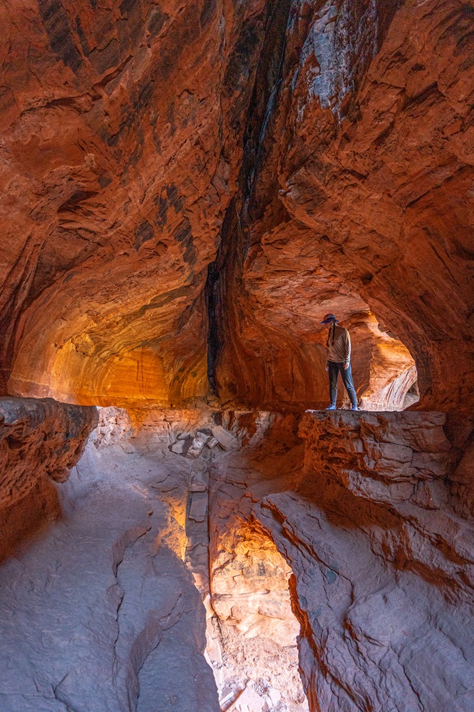 Woman standing on a rocky outcrop in the Soldier Pass Cave.