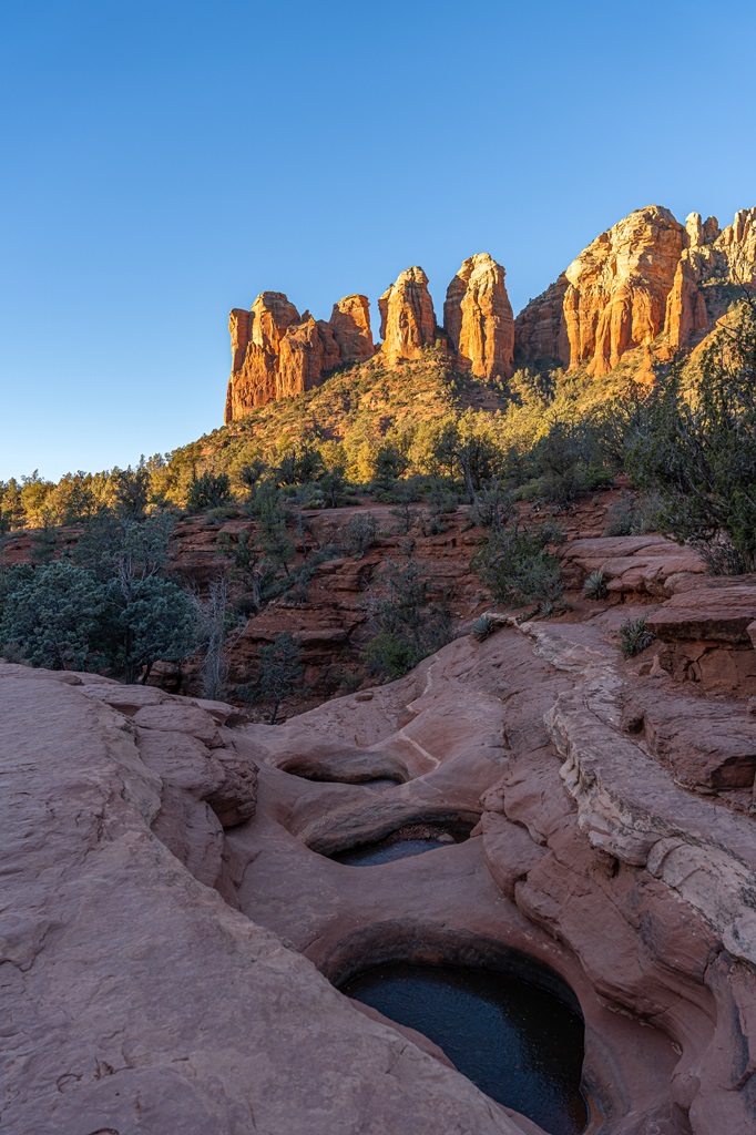 Seven Sacred Pools in the shade and Coffee Pot Rock illuminated by the early morning light along the Soldier Pass Trail during sunrise in Sedona.