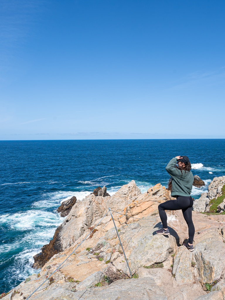 Woman standing on the rocks looking out at Pinnacle Cove along Point Lobos Loop.