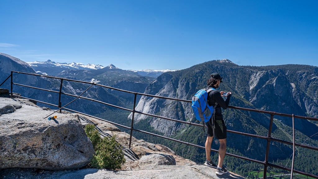 Man at Yosemite Point taking a picture of the views of Yosemite Falls.