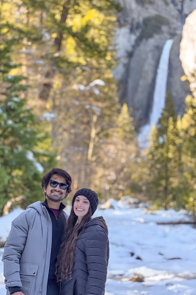 Man and woman posing for a picture in front of Lower Yosemite Falls.