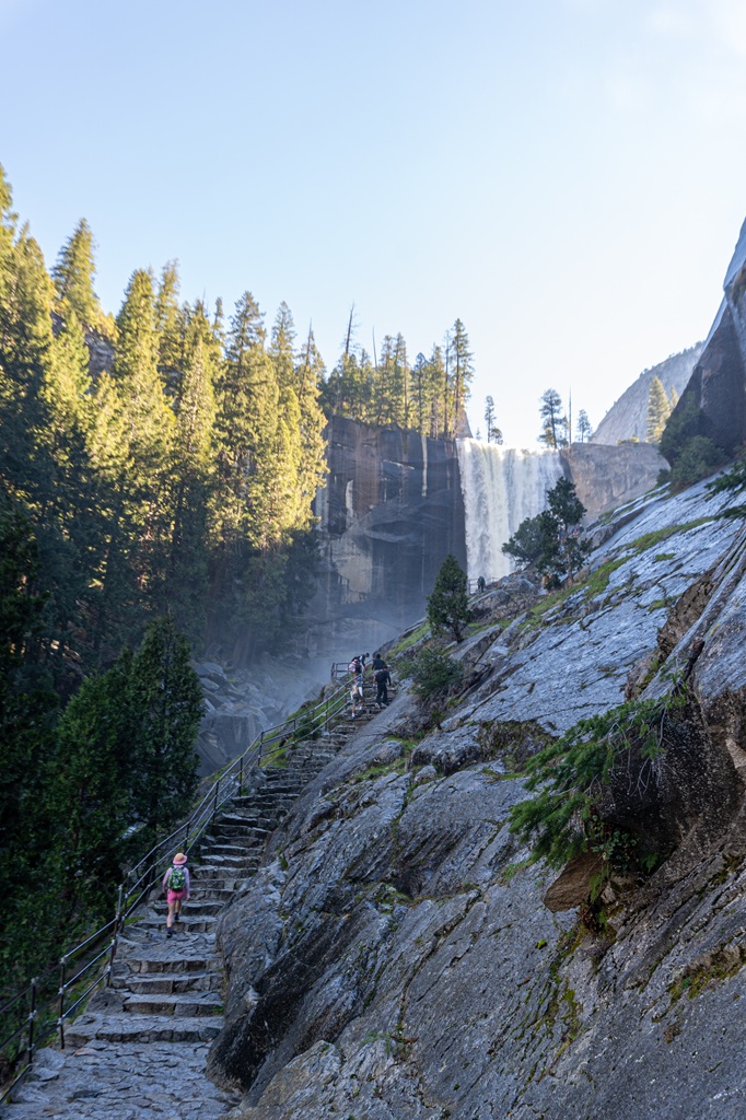 Woman climbing the granite steps along the Mist Trail towards Vernal Fall in Yosemite National Park.