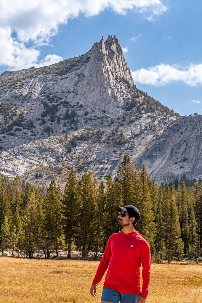 Man standing near a meadow with Cathedral Peak in the background.