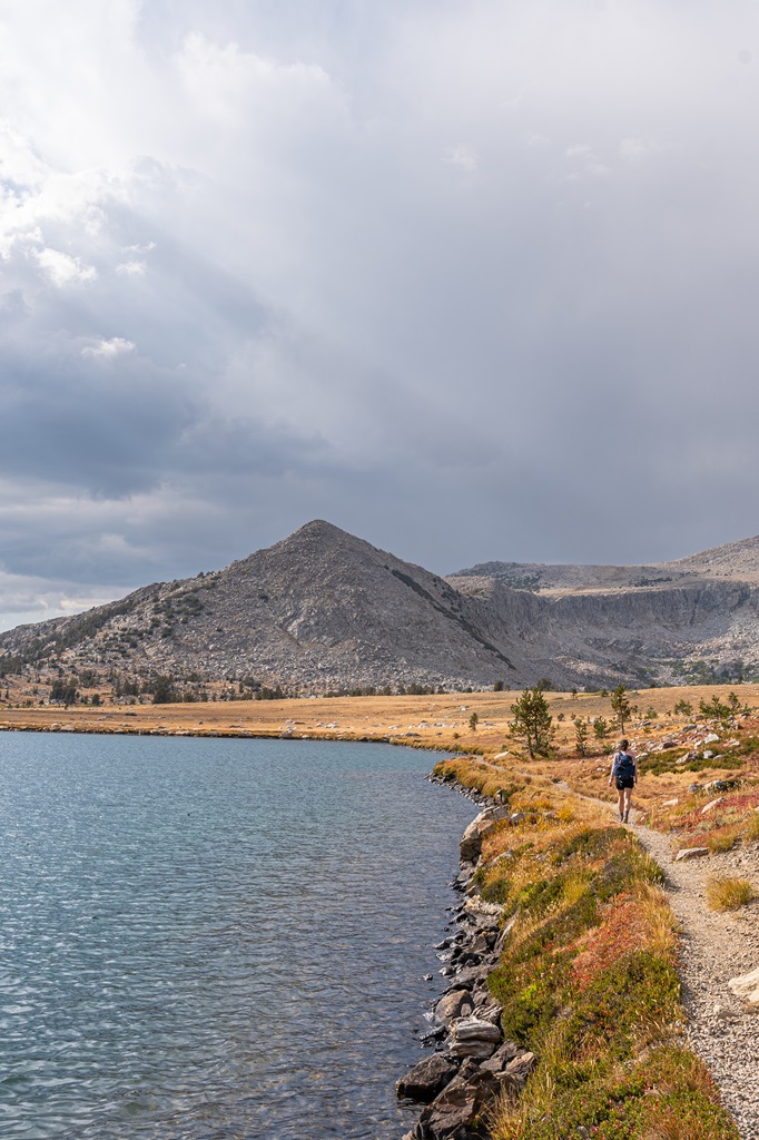 Woman hiking along the trail beside Middle Gaylor Lake in Yosemite.