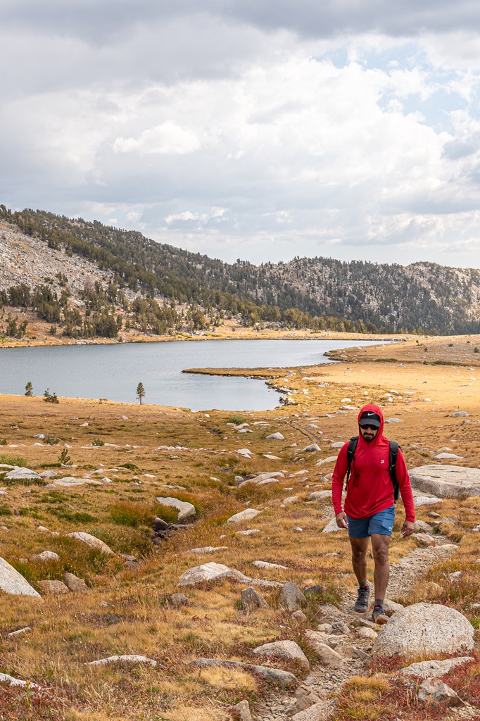 Man hiking along Gaylor Lakes Trail with Middle Gaylor Lake in the background.