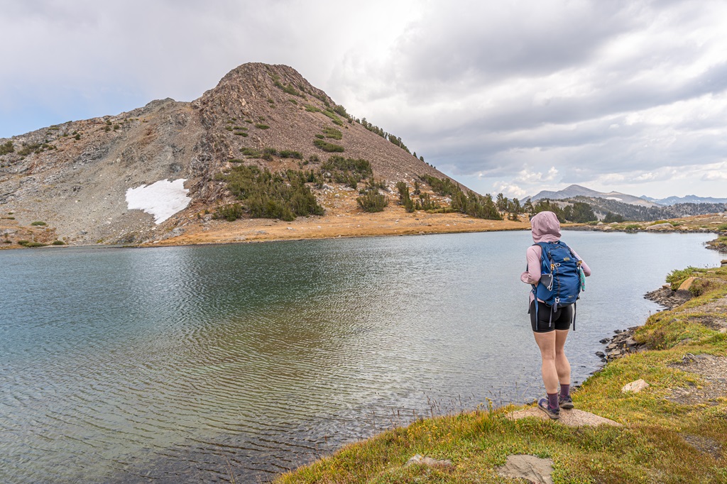 Woman standing at the shore of Upper Gaylor Lake with Gaylor Peak in the background.