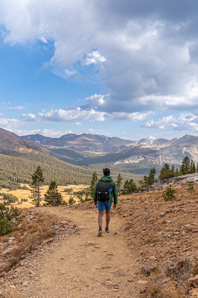 Man hiking along the Gaylor Lakes Trail with Sierra peaks in the distance.