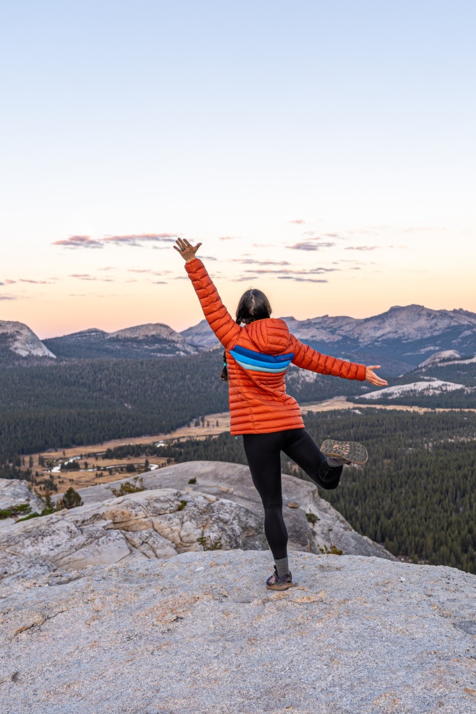 Woman posing on top of Lembert Dome during sunrise.