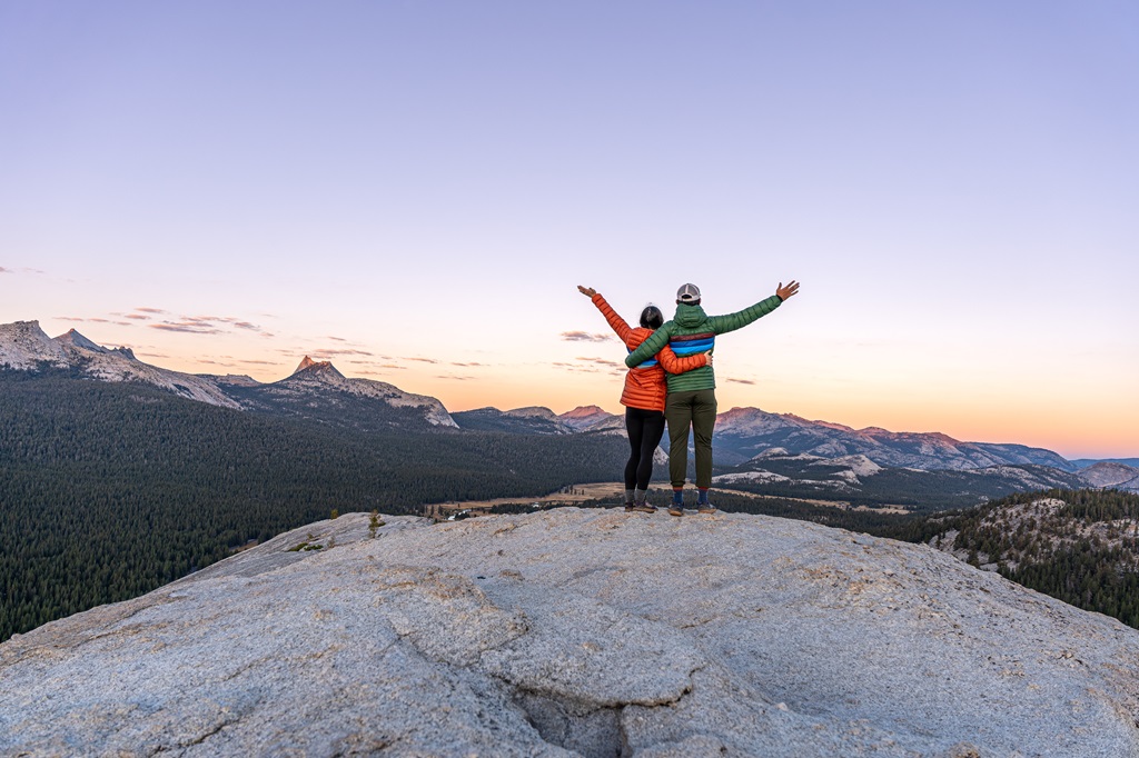 Man and woman standing at the top of Lembert Dome with arms in the air.