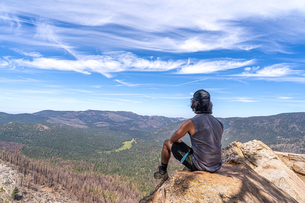 Man sitting on a rock at Wawona Point in Mariposa Grove looking at the views.