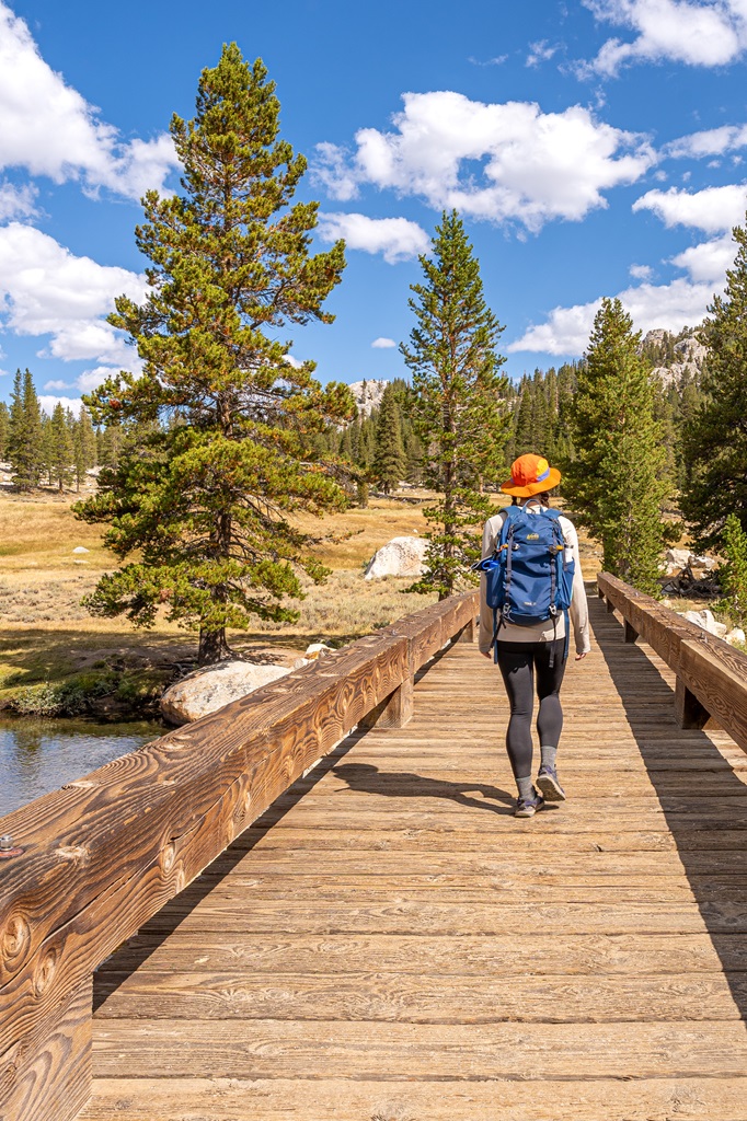 Woman walking over a footbridge towards Soda Springs and Parsons Lodge.