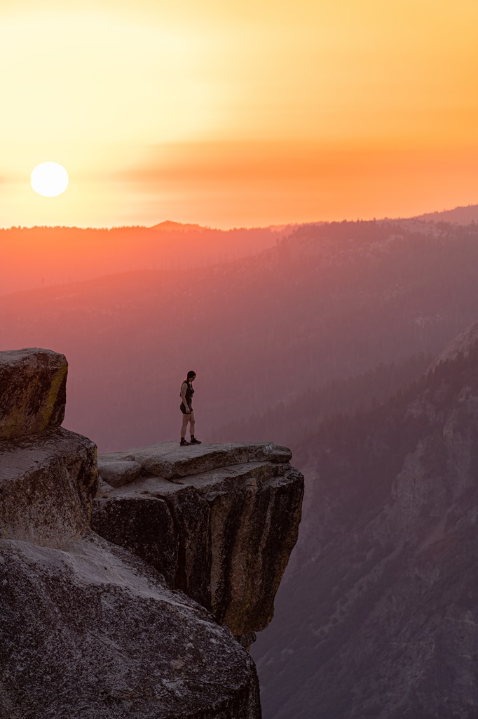 Woman standing on a rocky outcrop during sunset at Taft Point.