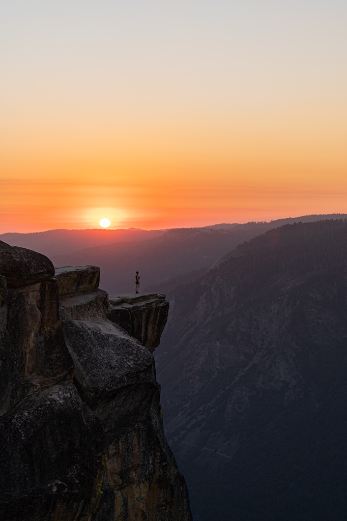 Woman standing on a rocky outcrop watching the sunset at Taft Point.