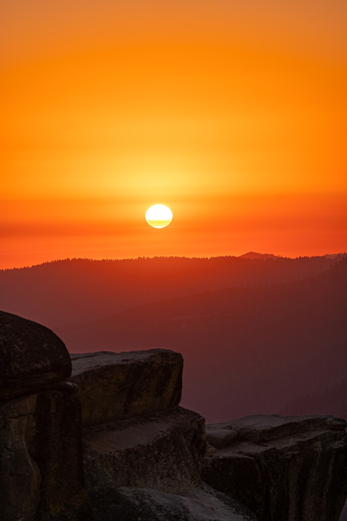 View of a vibrant sunset with bright orange and red colors shining of Taft Point's rocky outcrop.