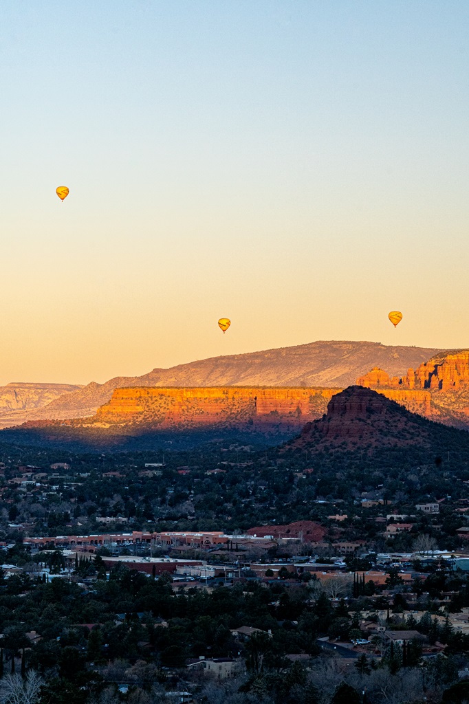 View of hot air balloons floating through the sky seen from Airport Mesa Vortex in Sedona.