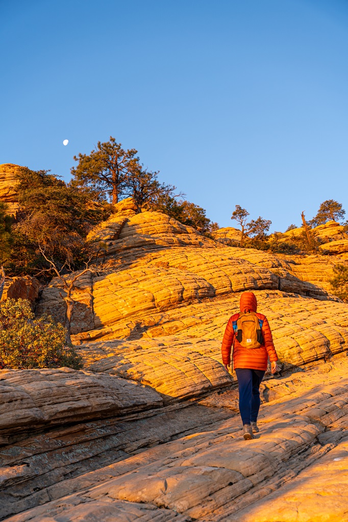 Woman hiking over steep, sandstone slabs along the Bear Mountain Trail in Sedona.