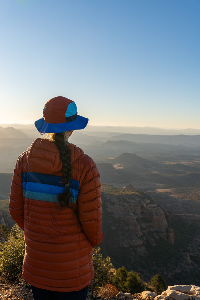 Woman standing on top of Bear Mountain in Sedona with views of Sedona's red rock formations.