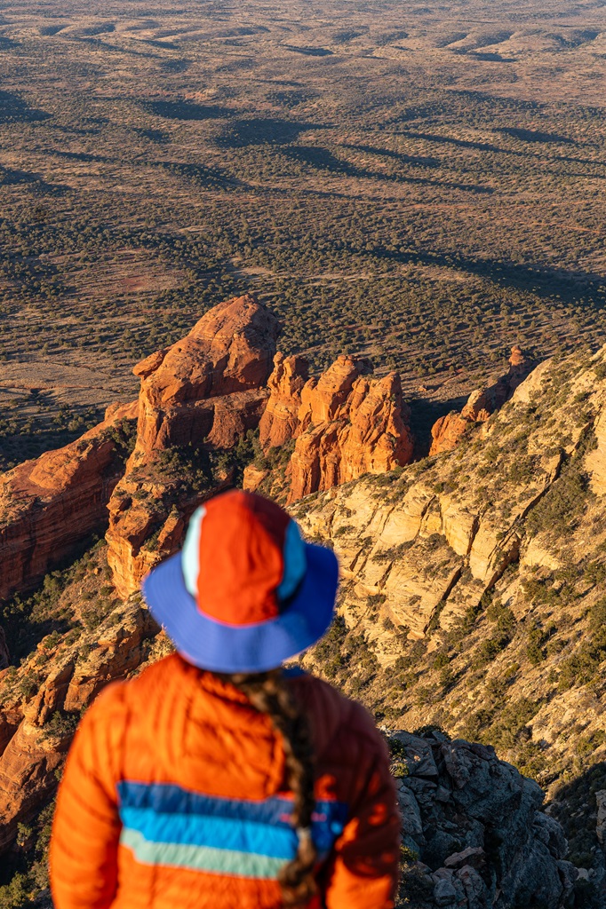 Woman standing at the summit of Bear Mountain looking out at the red rock landscape.