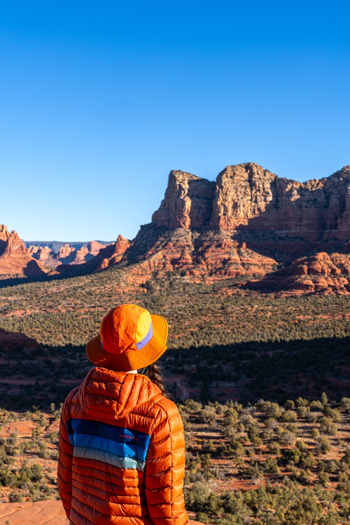 Woman standing on the upper section of the Bell Rock Climb after sunrise in Sedona.