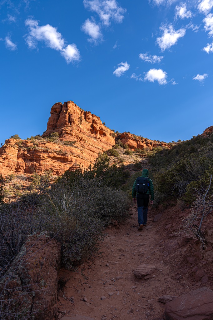 Man hiking along the Doe Mountain Trail in Sedona with Doe Mountain in the background.