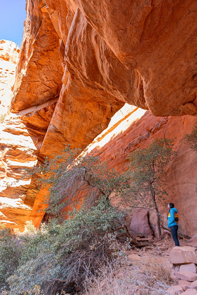 Woman standing underneath Fay Canyon Arch in Sedona.