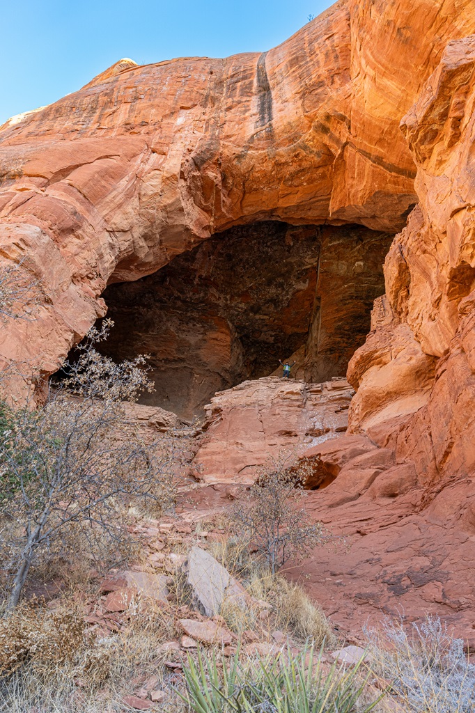 Man standing inside the Keyhole Cave with hands in the air.