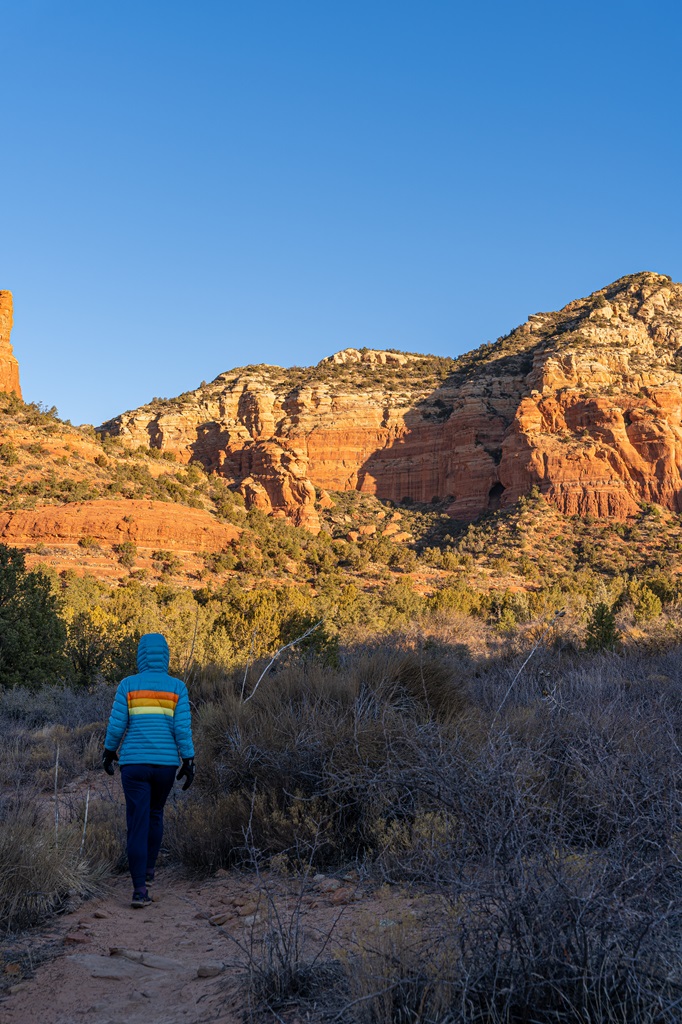 Woman hiking along a social trail towards Keyhole Cave in Sedona.