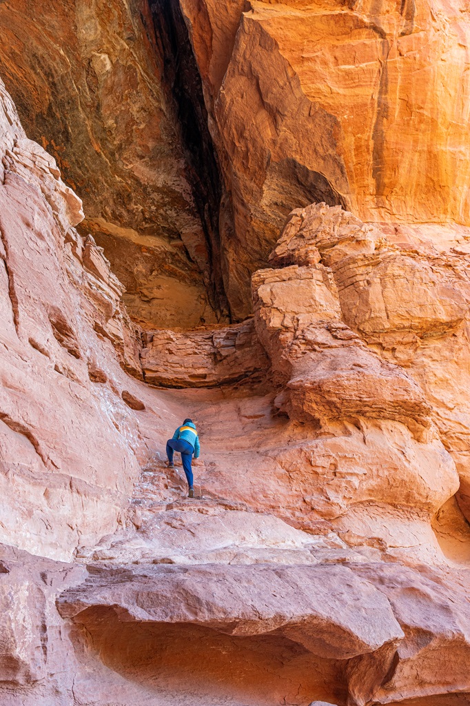 Woman climbing a class III route into the Keyhole Cave in Sedona.