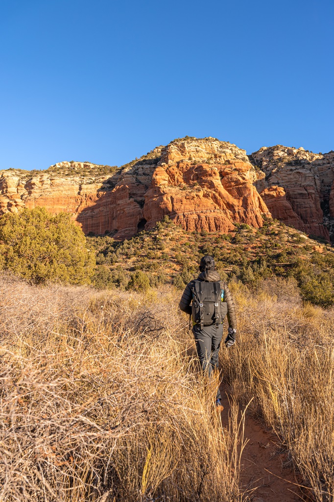 Man hiking along a social trail towards Keyhole Cave in Sedona in January.