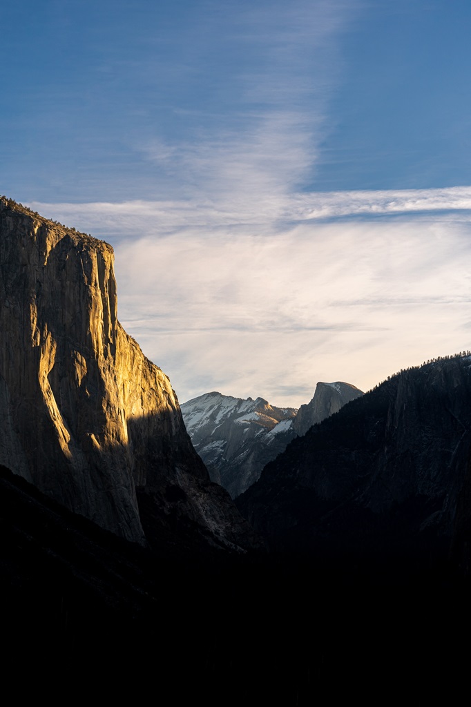 Sunrise at Tunnel View in Yosemite with sun shining on El Capitan and snow-covered High Sierra Peaks and Half Dome in the distance.