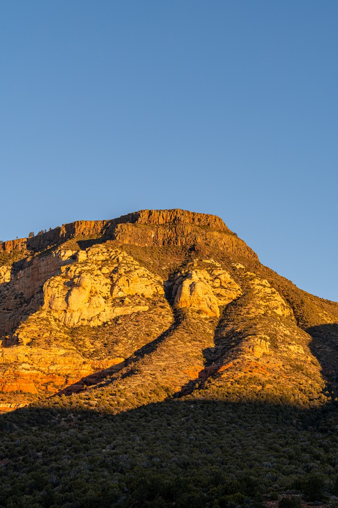 Close-up shot of Wilson Mountain illuminated by the sun rising over the horizon.